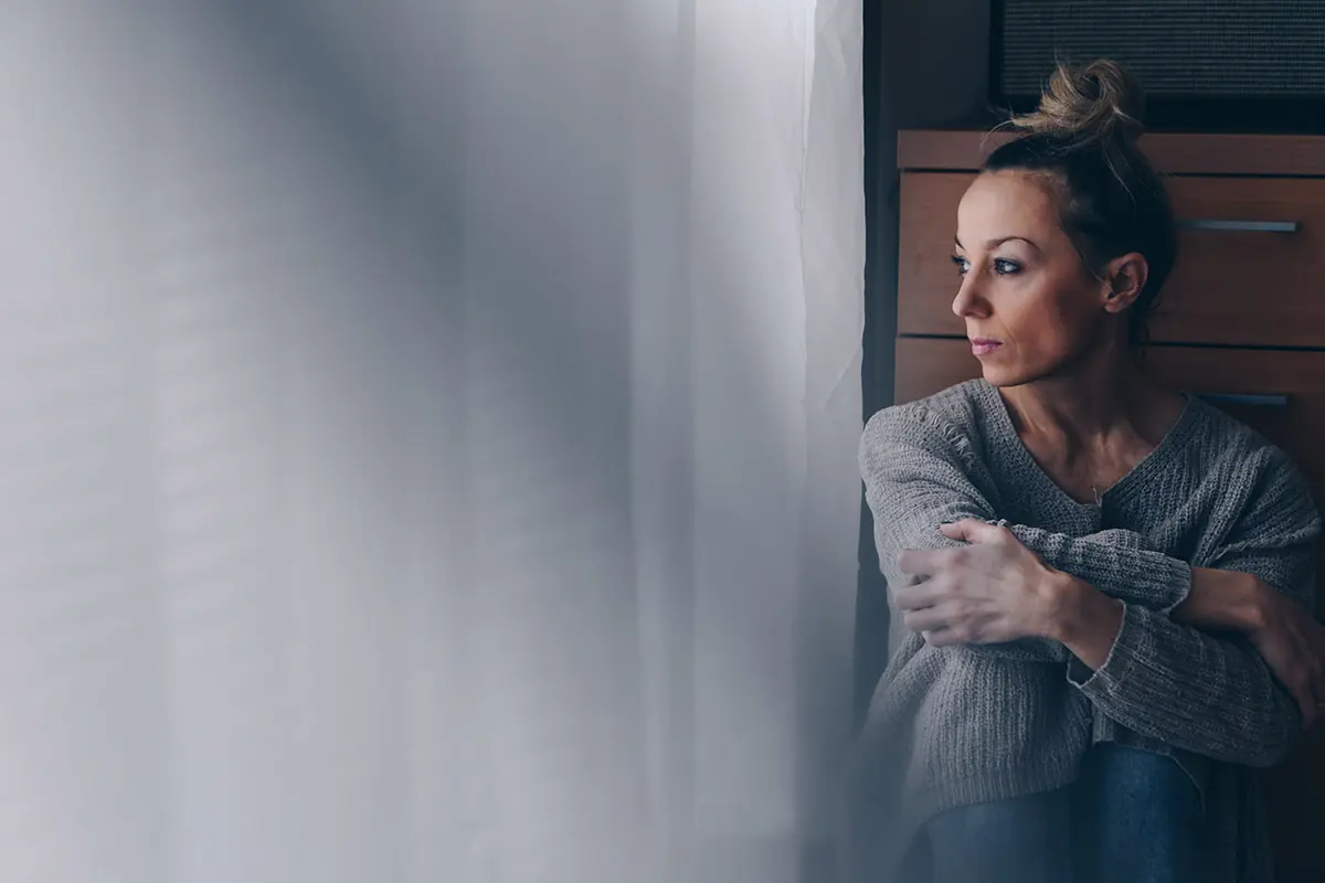 woman staring out a window considering signs of rivotril addiction