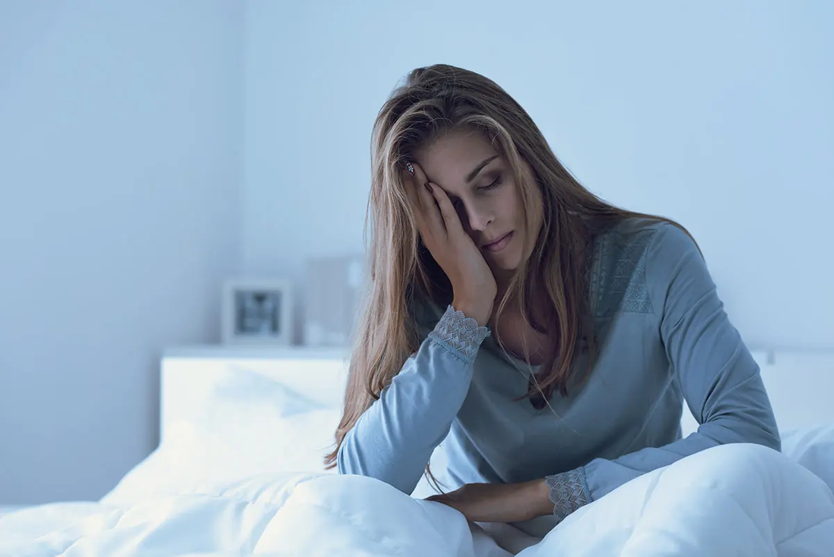 a tired woman in bed struggles with the long-term side effects of sleeping pills
