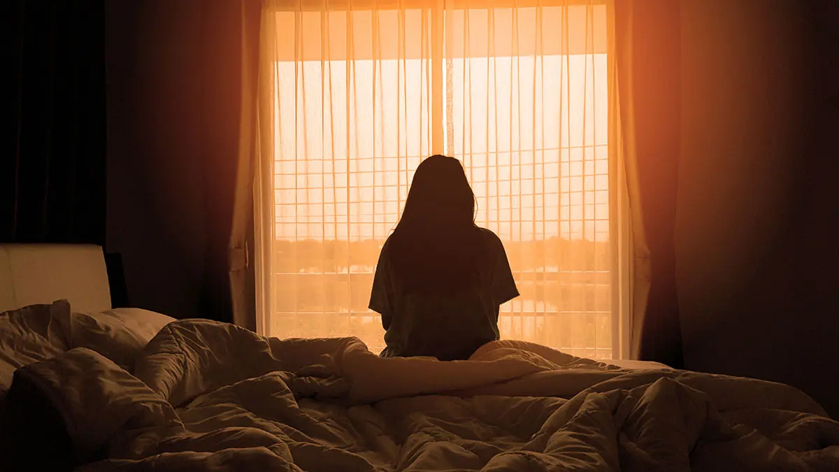 a person sits up in bed waking up from being blackout drunk