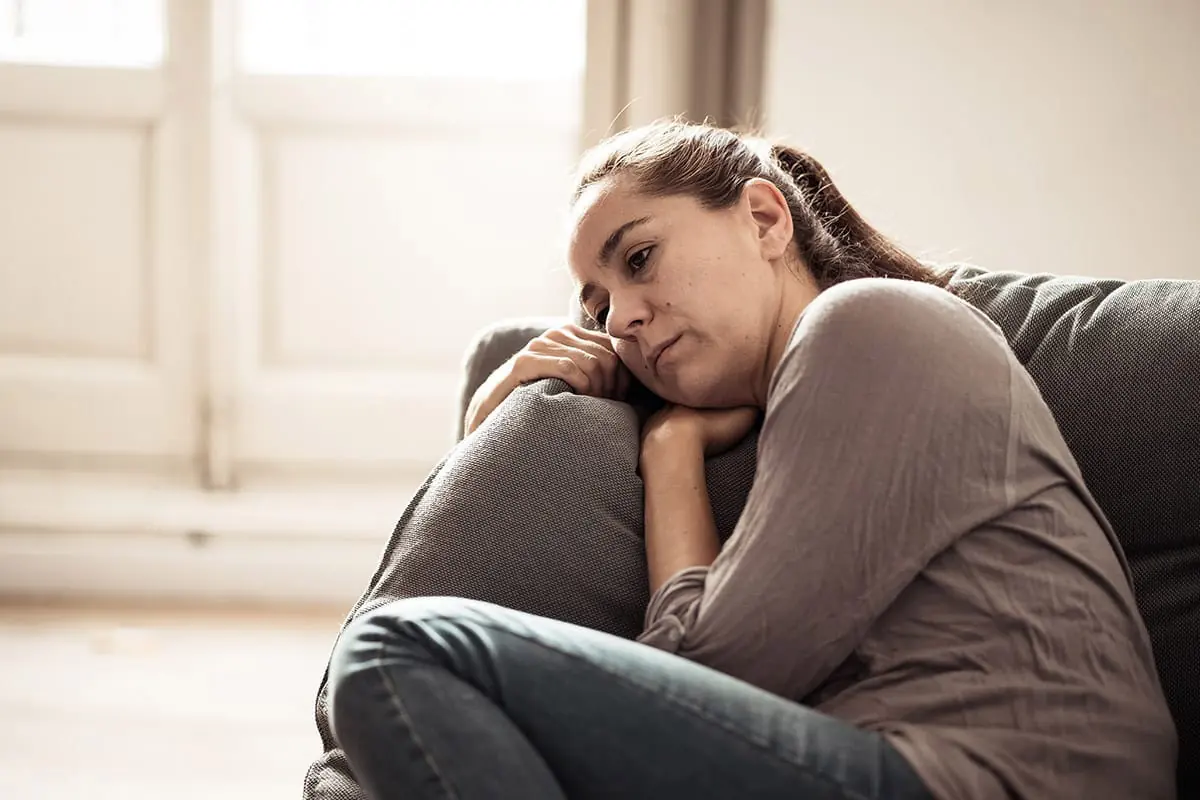 young woman lays on couch looking depressed and listless wondering are cocaine withdrawal symptoms different for women