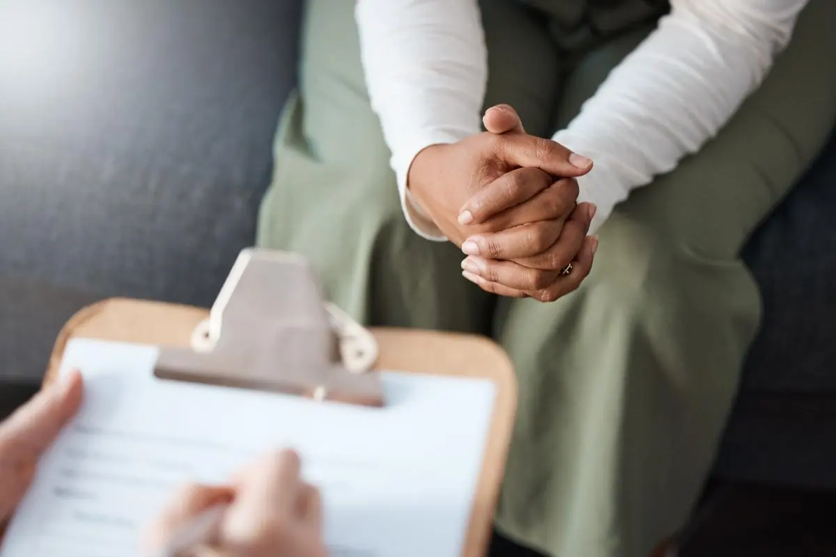 close up of the clasped hands of a nervous patient asking an addiction treatment specialist why Klonopin the controlled substance Clonazepam is so readily abused