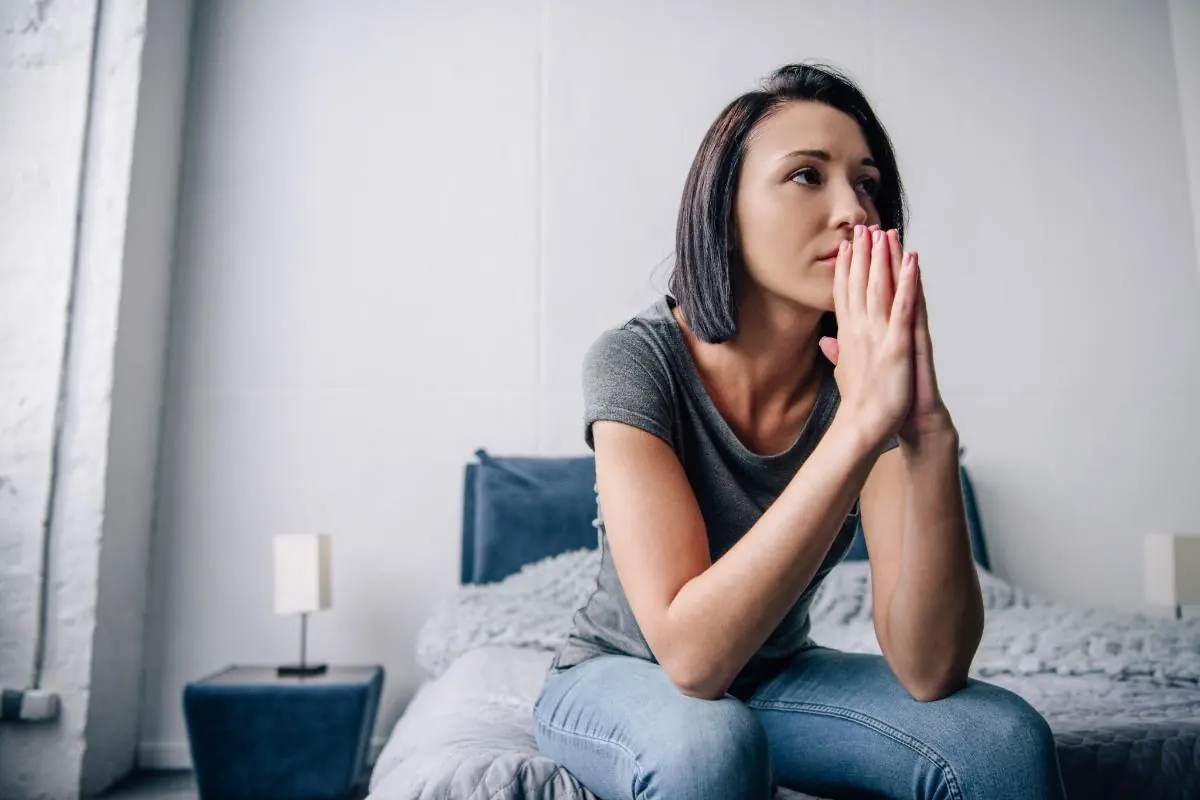 young woman sitting on the end of her bed struggling with understanding vyvanse common side effects for women.