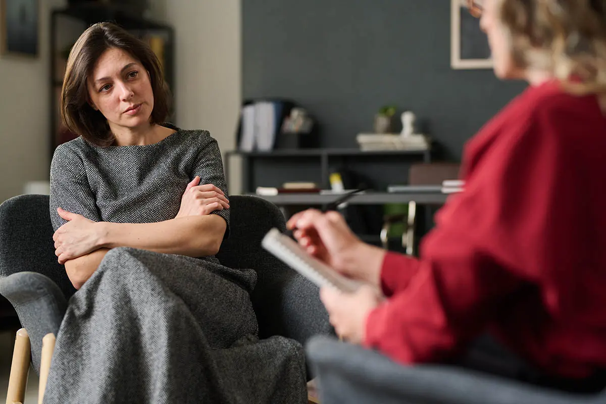 female behavioral health specialist talking to mature woman in an office setting and have a serious discussion about what is post-traumatic stress disorder.
