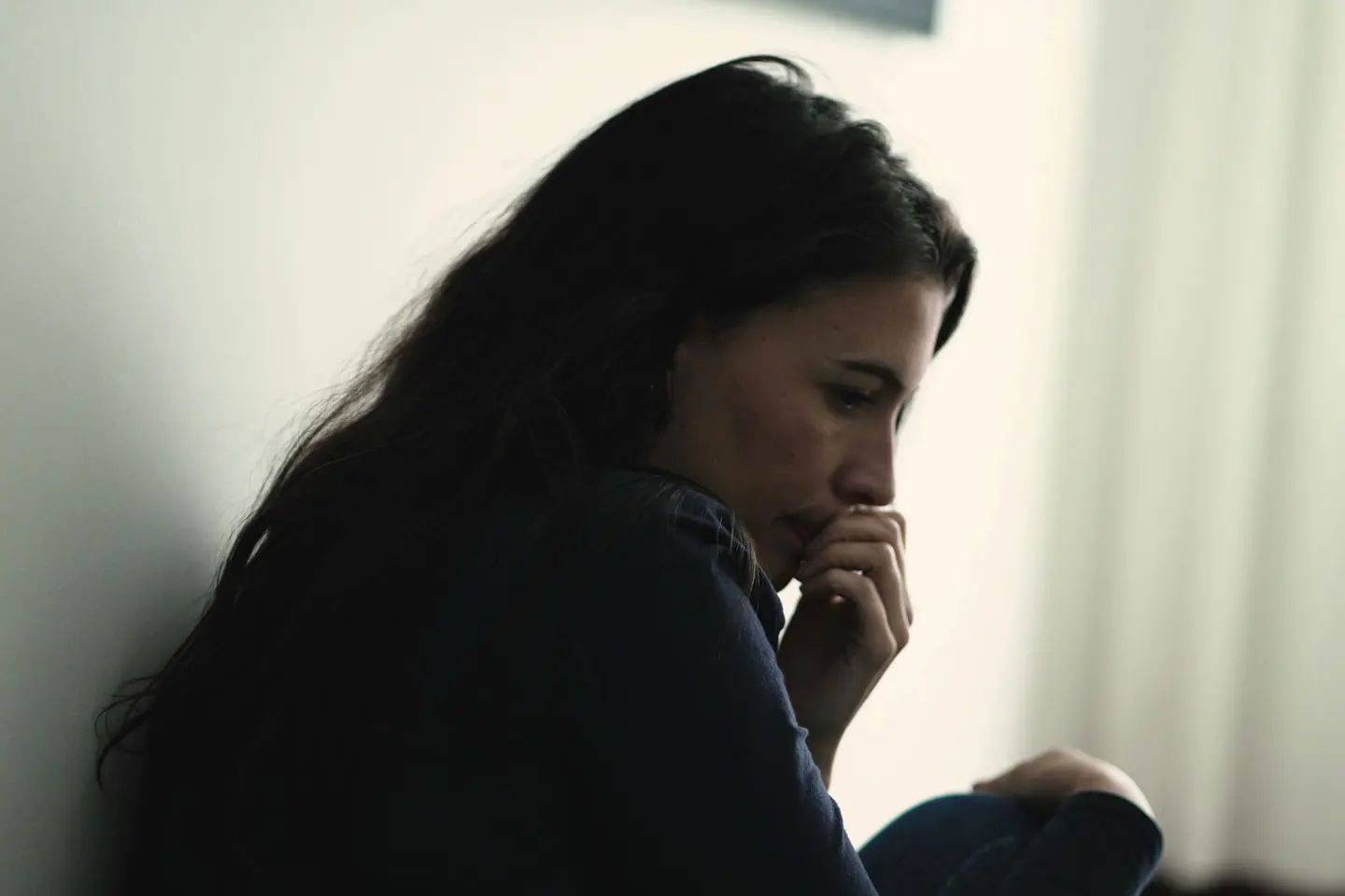 distraught woman seated alone in her room looking uncertain about the effects of alcohol on women's health