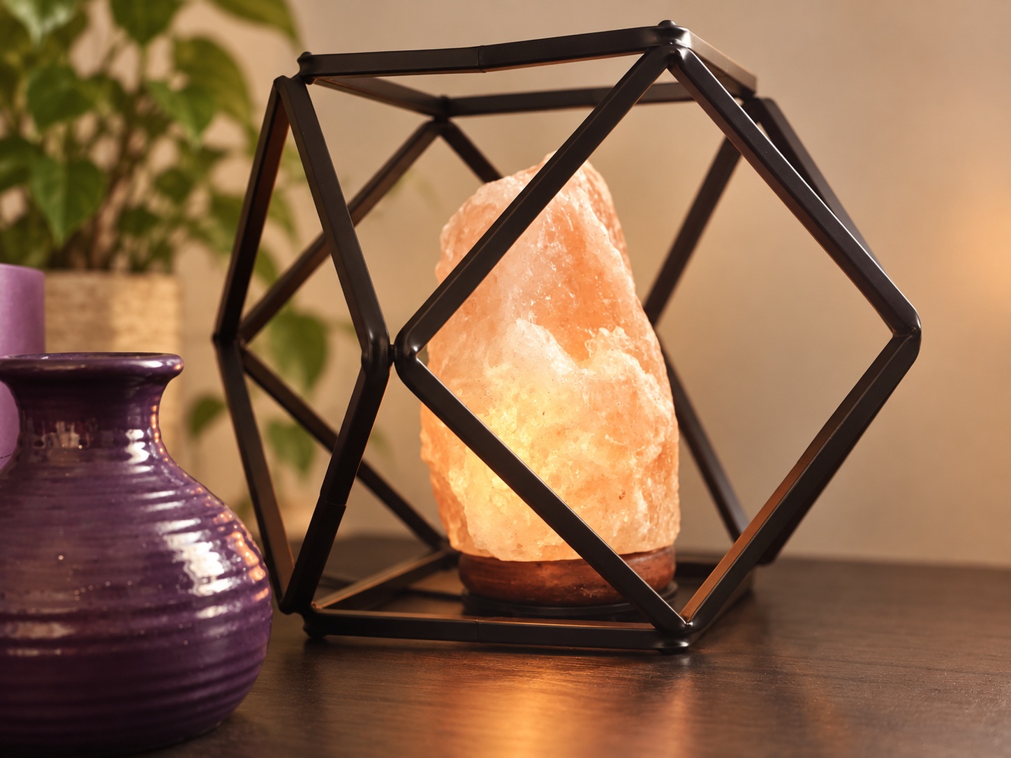 Pink stone lamp in a black frame beside a purple vase