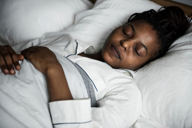 How to Naturally Fall Asleep While Being Sober young woman sleeping peacefully in bed after learning how to fall asleep while being sober