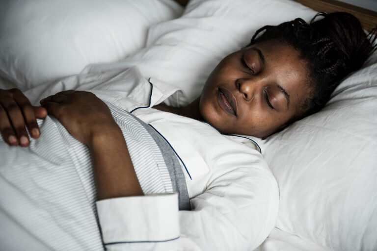 young woman sleeping peacefully in bed after learning how to fall asleep while being sober