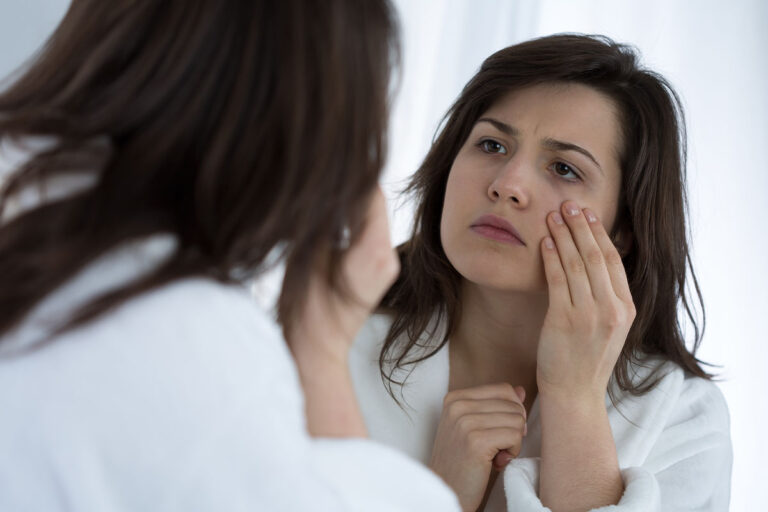 Woman looking in mirror and thinking that she needs body image treatment