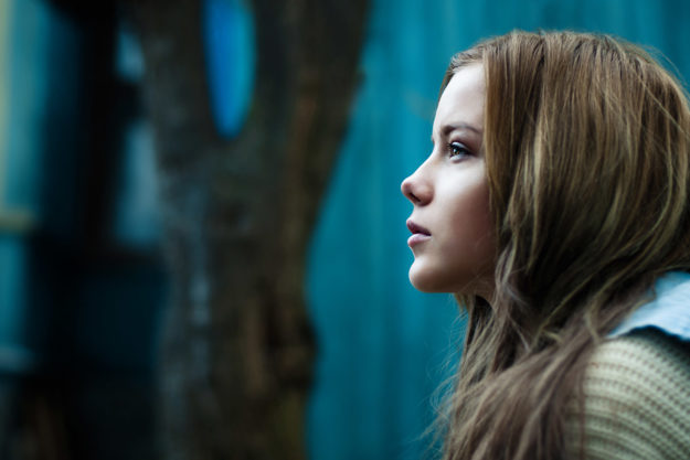 The Dangers of Teenage Drug Abuse teenage girl sitting alone outside staring into space and unaware of the dangers of teenage drug abuse