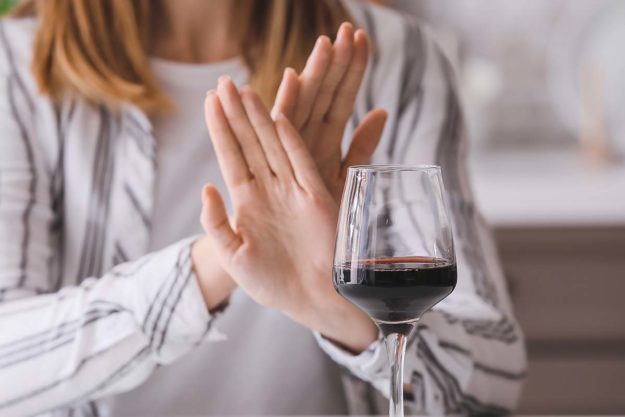 Woman refusing to drink wine at home. Concept of alcoholism a women's alcohol rehab has helped this woman cope