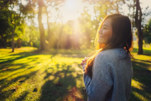 How To Improve Gut Health for Women a person smiles in the sunshine enjoying the benefits of good gut health for women
