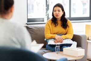 young woman looking concerned as she discusses a dual diagnosis treatment program with her therapist
