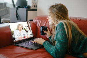 A woman on a couch uses a laptop for a virtual intensive outpatient program in rural Colorado.