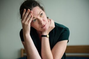 A woman on a bed, hands on her head, conveying the mental strain associated with Rivotril abuse and addiction