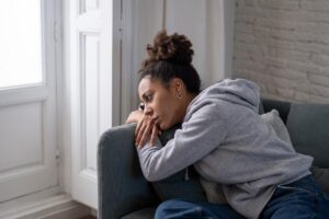 young woman slumped on couch considering whether or not to take Am I an Alcoholic questionairre