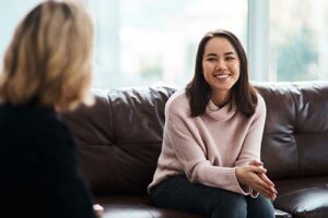 A woman discusses the merits of a partial hospitalization program with her therapist on a couch