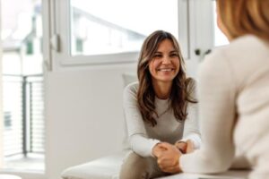 Two women sit together on a couch, symbolizing support on the pathway to substance use disorder recovery