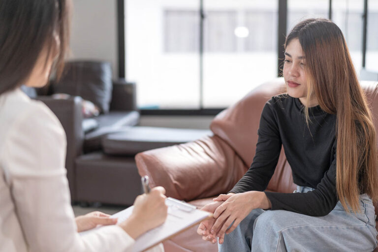 What Causes Bipolar Disorder female behavioral health specialist speaking with young woman in an office setting about what causes bipolar disorder
