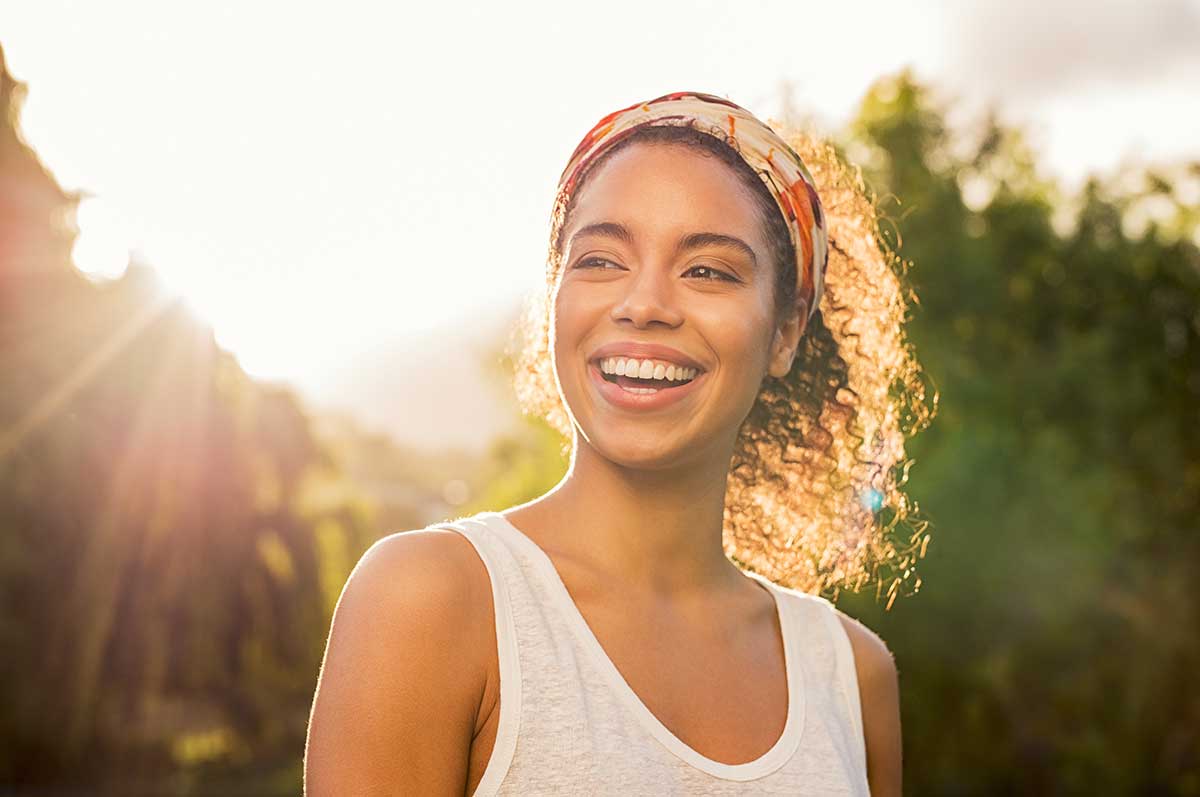 How-to-Set-Healthy-Boundaries-for-Your-Mental-Health smiling young woman walking on a sunny day after learning how to set boundaries for your mental health