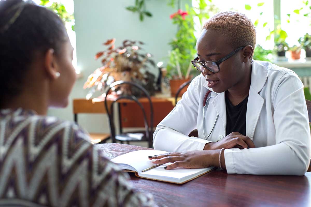 female behavioral health specialist meeting with young woman in an office setting to explain what to expect after TMS treatment.
