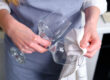woman drying two clean wine glasses in preparation of drinking without realizing the alcohol and cancer risk in women