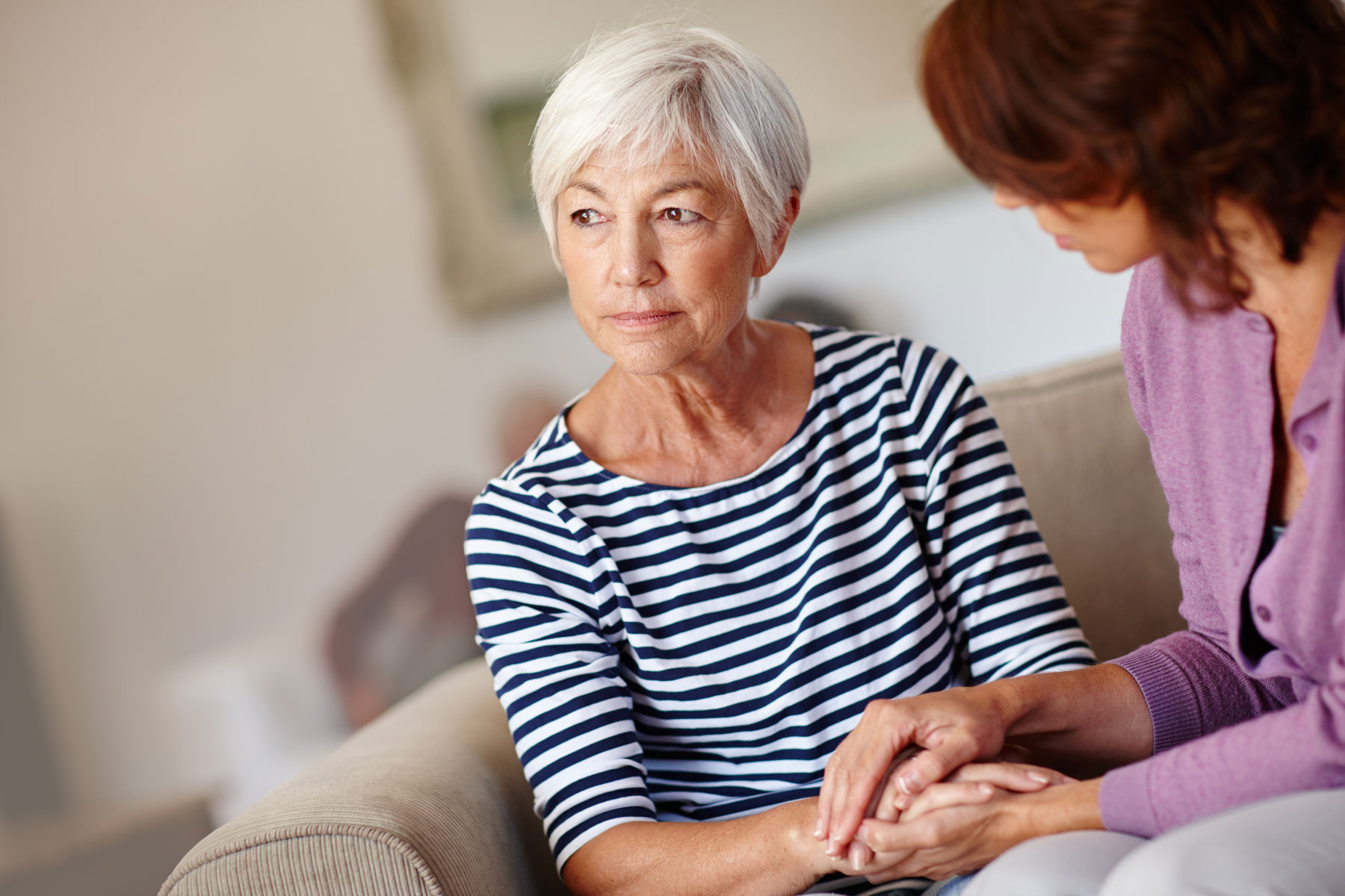 middle-aged woman seated on the couuch with her older mother wondering what to do when your mom drinks too much