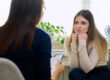 A woman with PTSD is being treated at Women's Recovery. She is leaning forward, listening to her therapist.